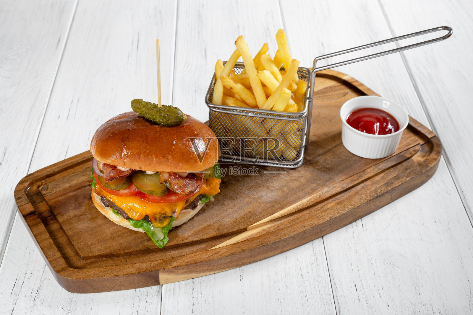木桌子上放着一个汉堡和一篮子加了番茄酱的薯条照片摄影图片