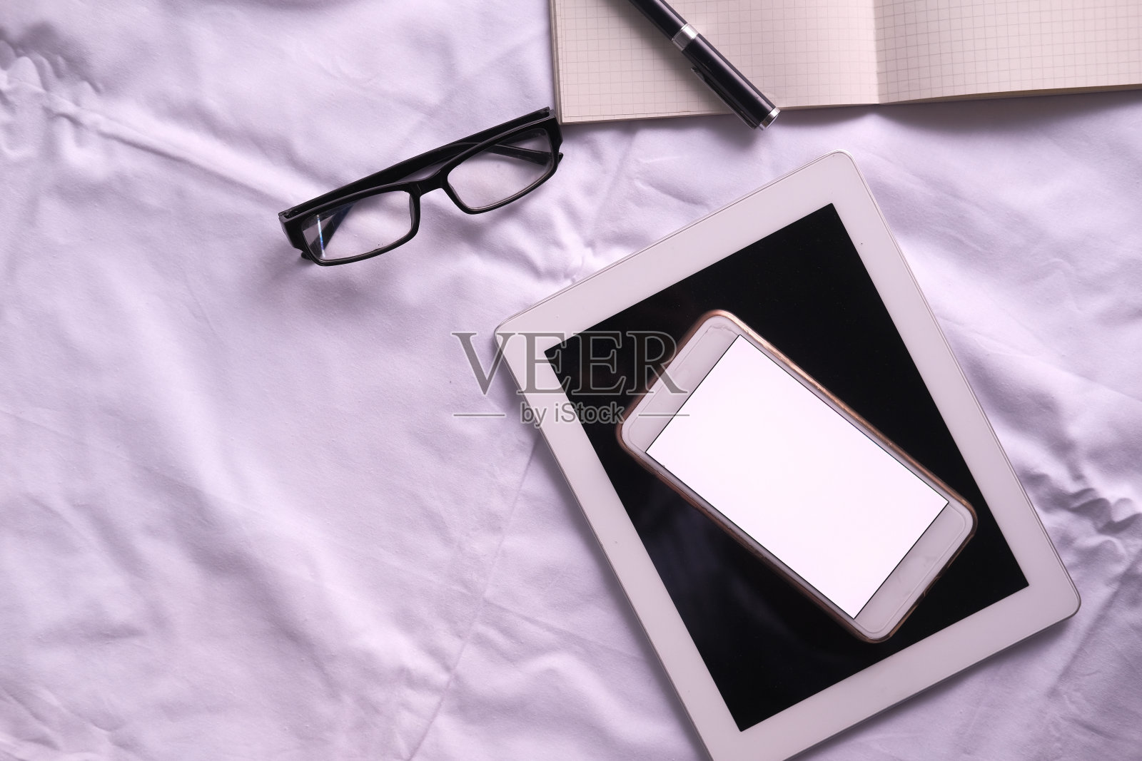 俯视图的数字平板电脑智能手机在床上照片摄影图片