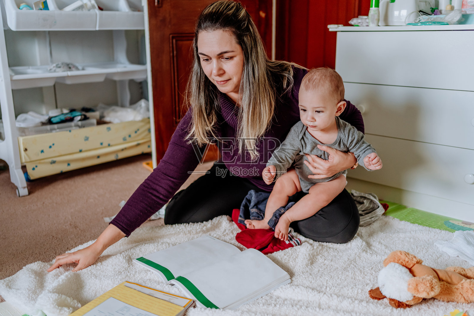 一边照顾男婴一边学习的忙碌母亲照片摄影图片
