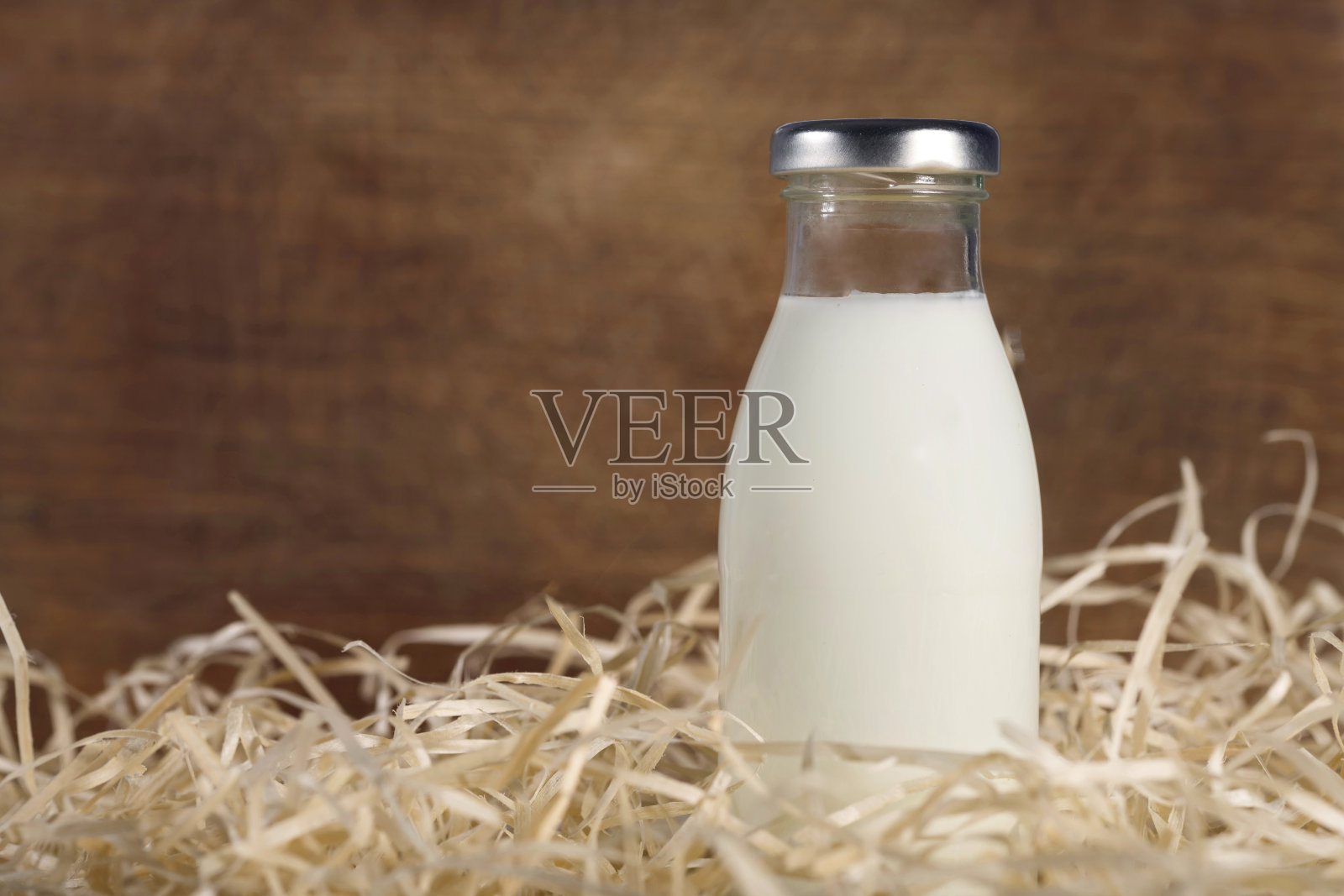 干草上的一瓶新鲜牛奶,木质背景。健康食品。牛奶产品。照片摄影图片
