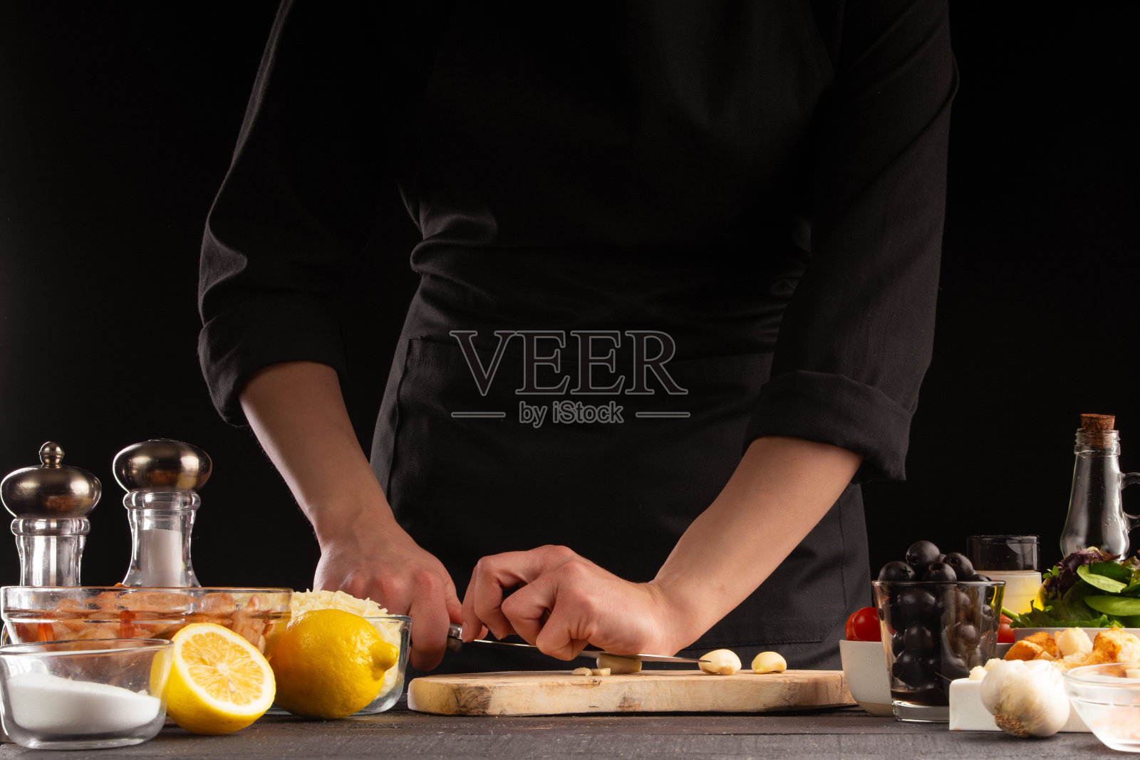 厨师烹饪时切蒜。以蔬菜为背景。烹饪,美味又健康的食物。照片摄影图片