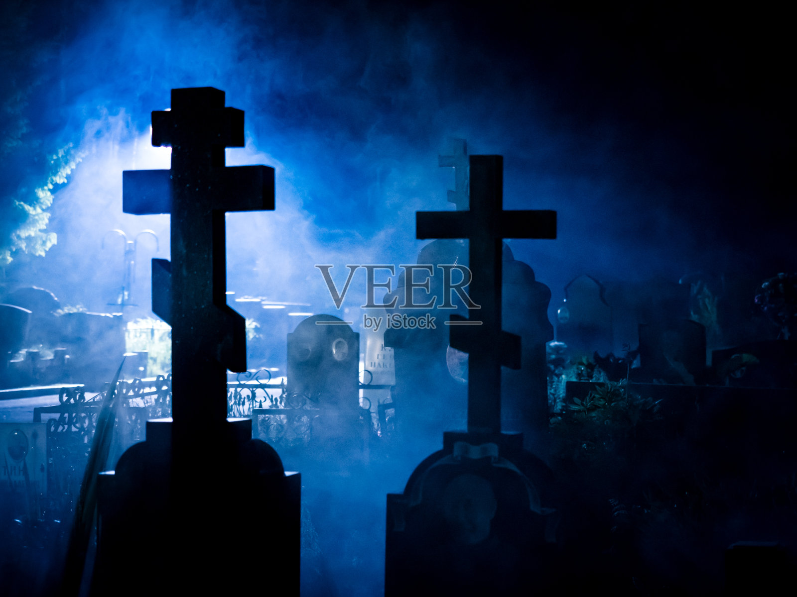 十字架和墓碑的剪影在雾蒙蒙的蓝色夜晚照片摄影图片