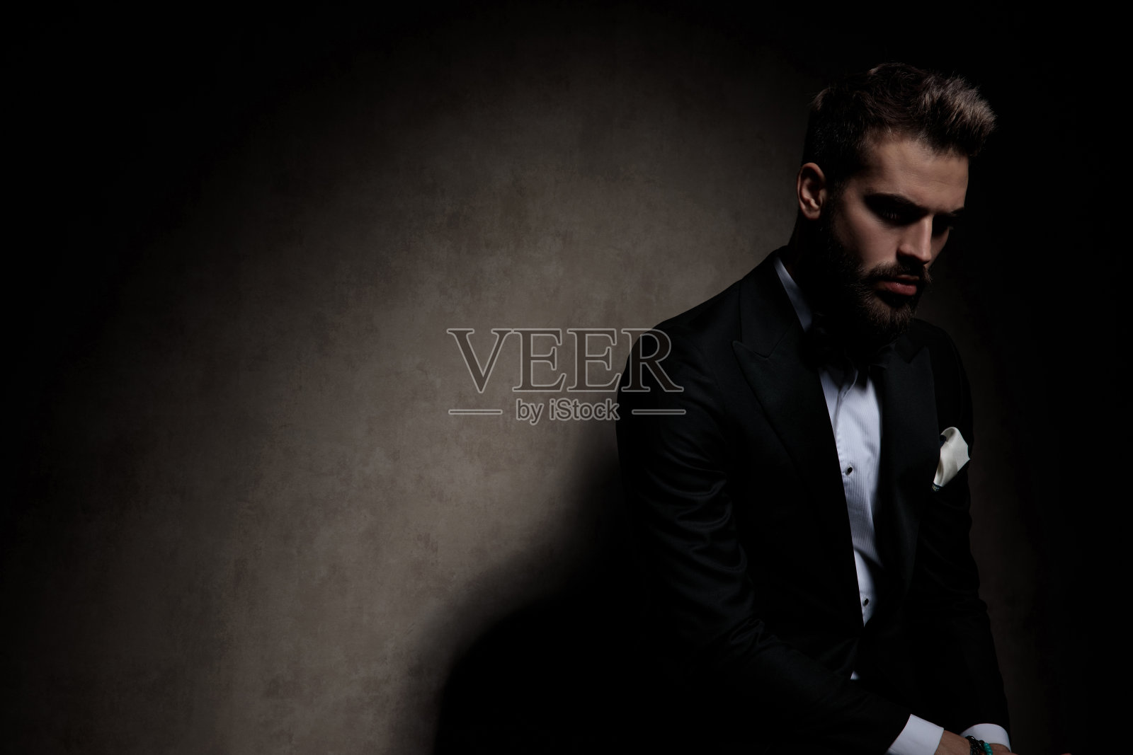 年轻的商人坐着,戏剧性地往下看照片摄影图片