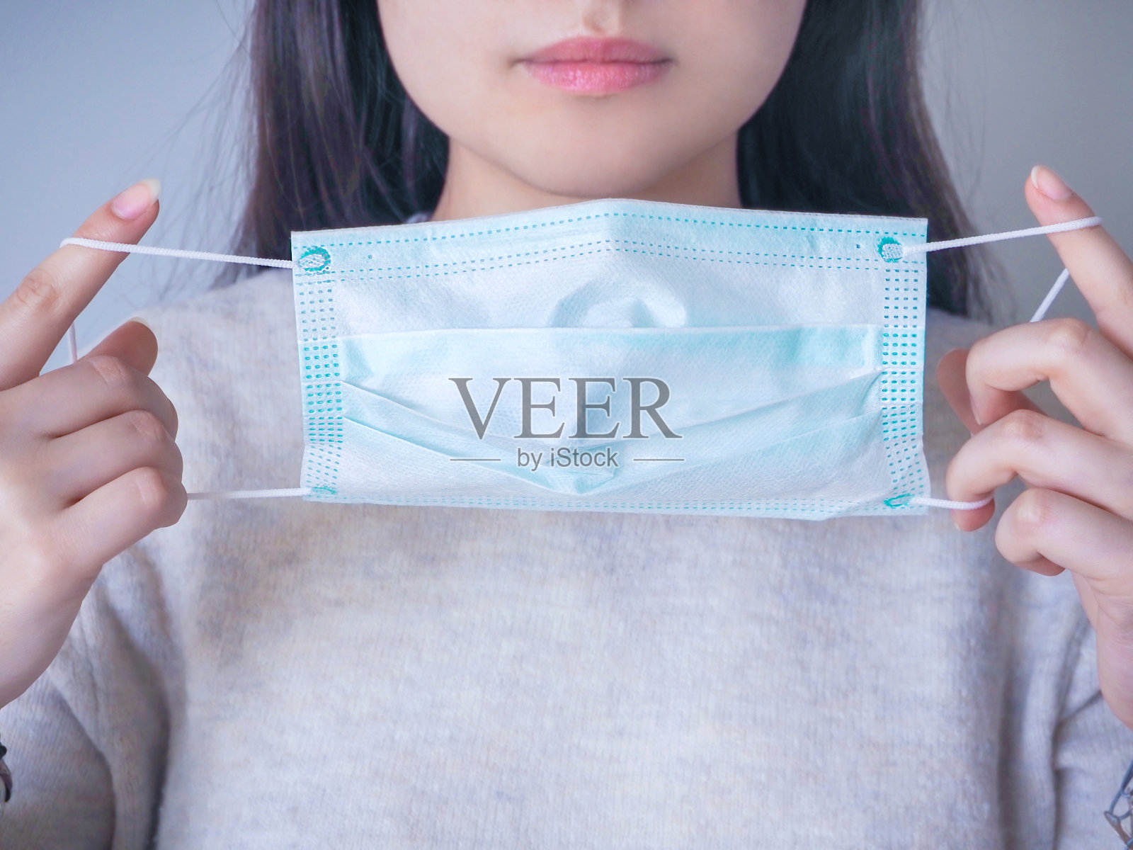 流行的冠状病毒。近距离拍摄一名年轻女子戴上外科口罩以预防病毒。照片摄影图片