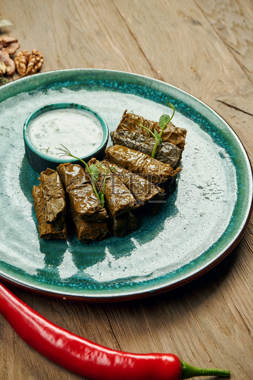 传统的格鲁吉亚dolma米饭,葡萄叶拌肉末,放在蓝色的盘子里,配上酸奶酱。木头的背景。前视图。Sarma照片摄影图片