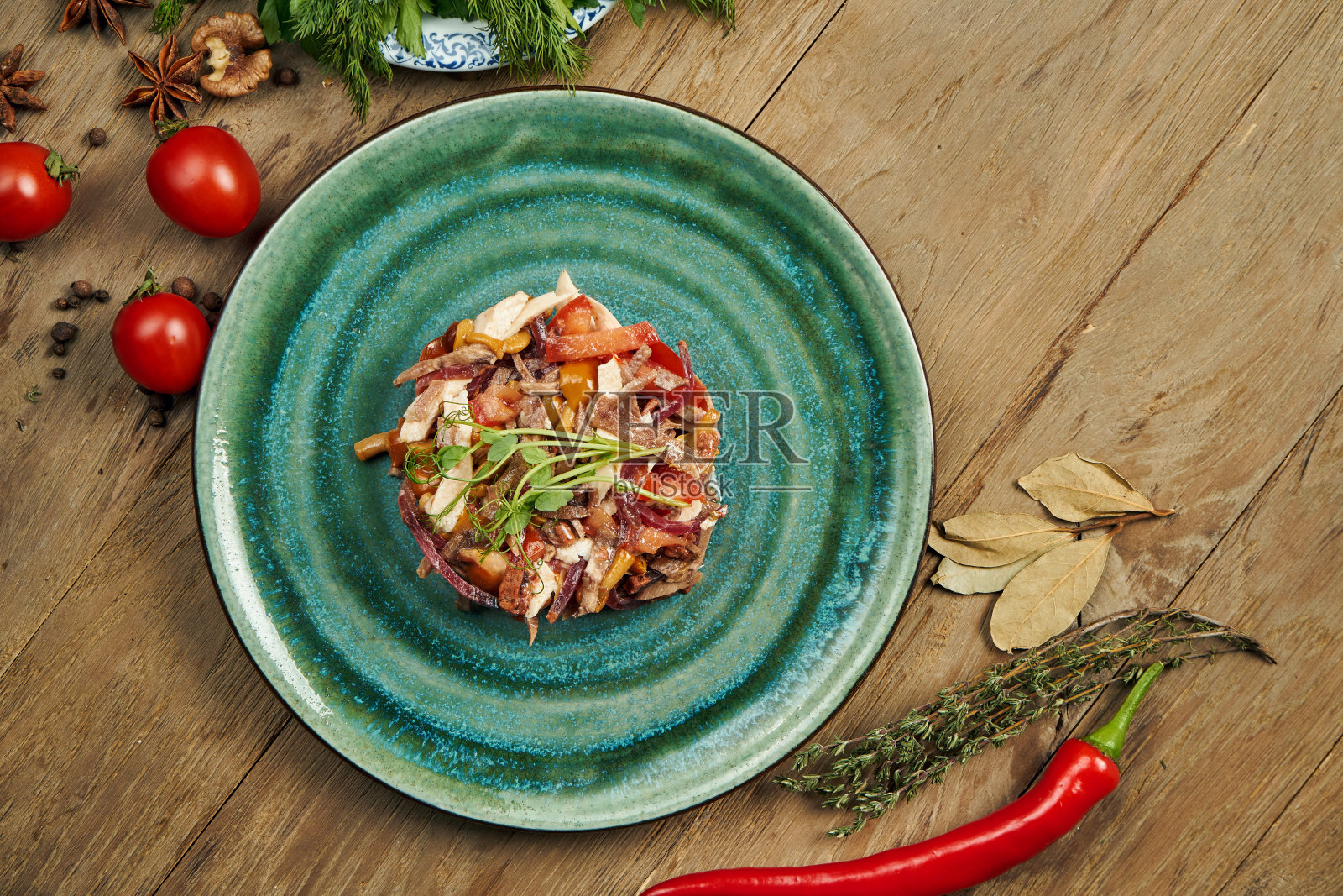 配着番茄、蘑菇罐头、洋葱和煮牛肉的沙拉,放在一个蓝色的盘子里,背景是木制的。斯拉夫沙拉麦地那。近距离照片摄影图片