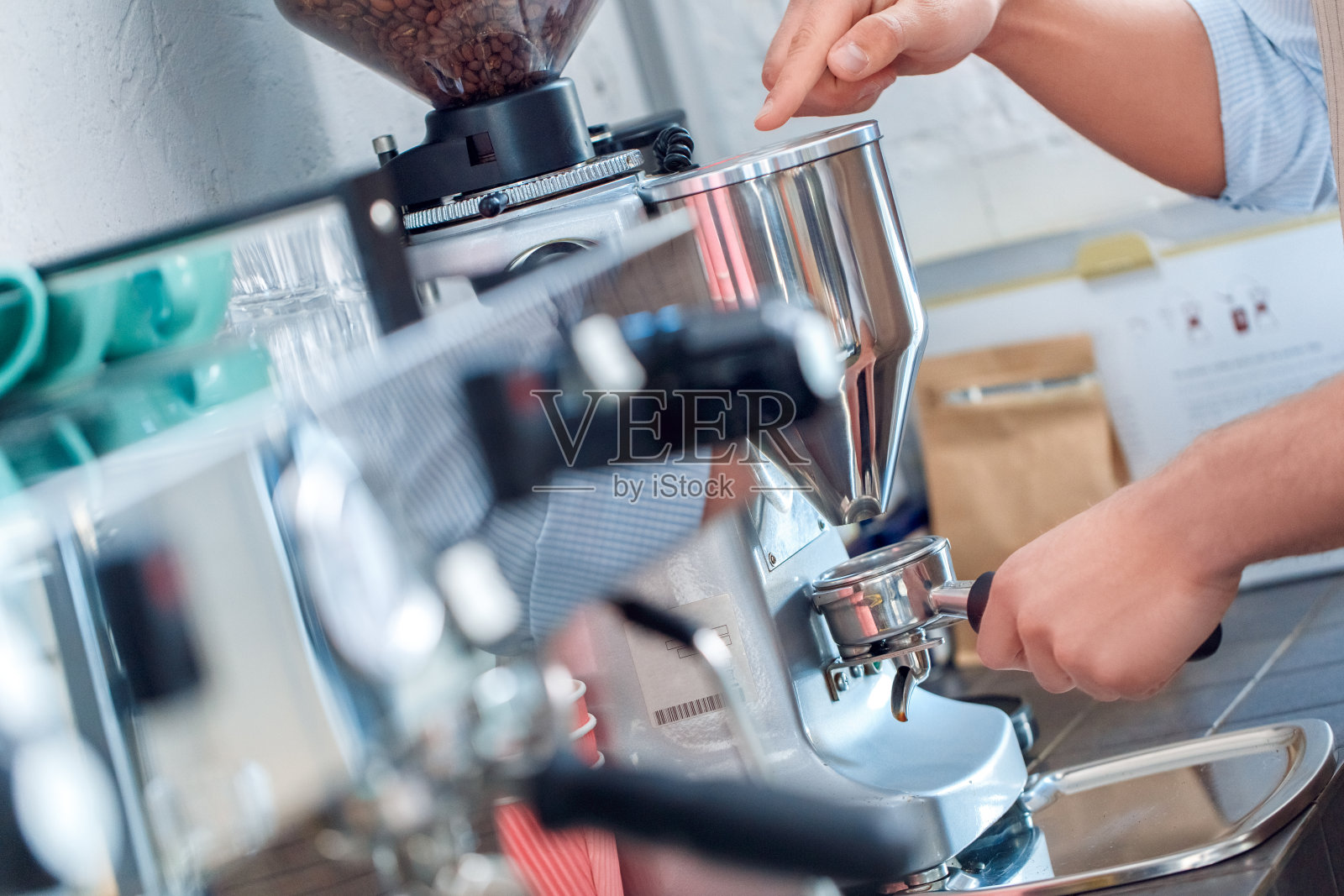 咖啡的激情。年轻的咖啡师在咖啡店使用电动咖啡研磨机做出完美的咖啡渣特写照片摄影图片