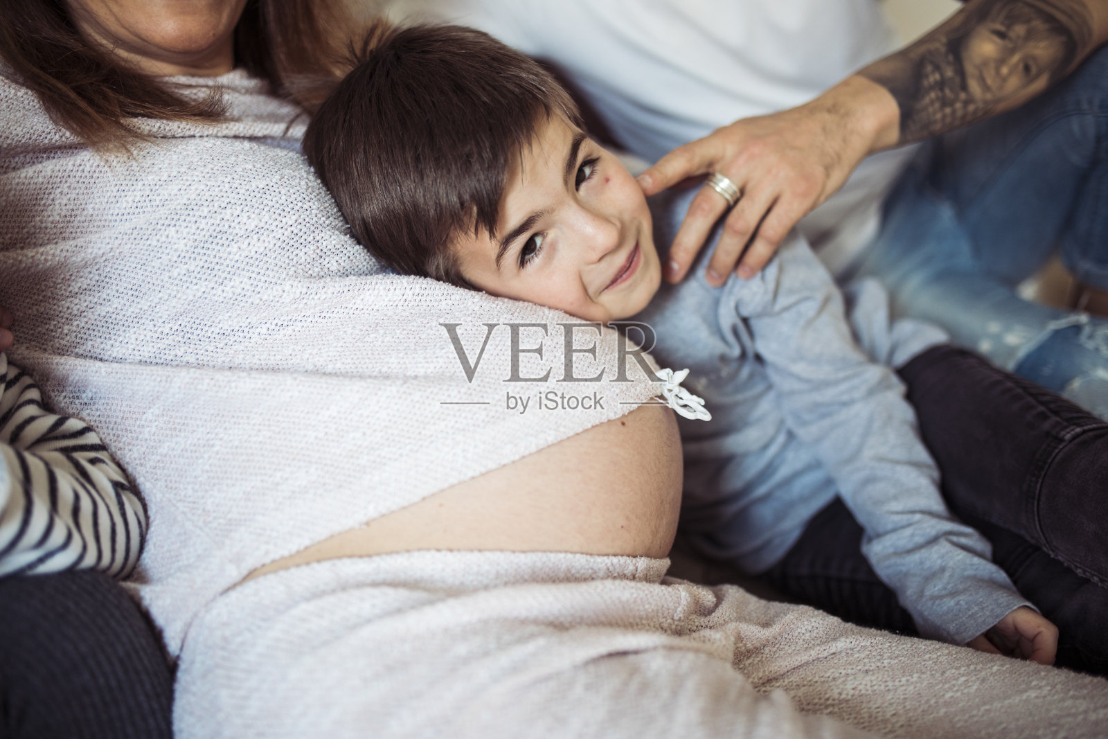 男孩把头放在妈妈的肚子上照片摄影图片