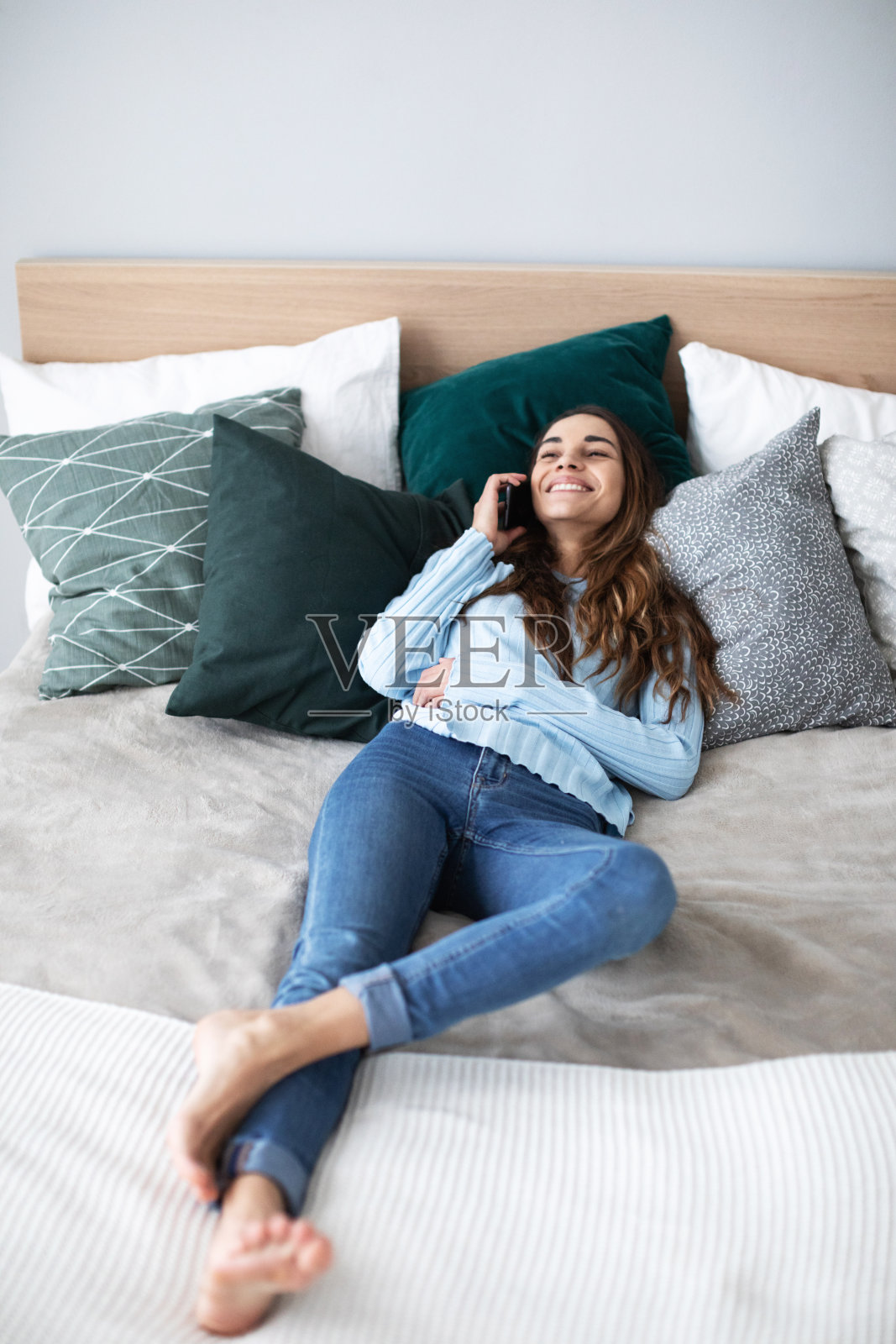 年轻漂亮的女人躺在沙发上打电话。照片摄影图片