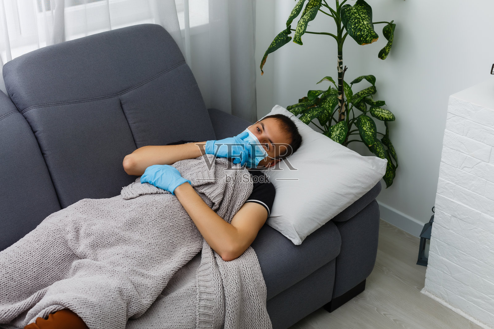 戴口罩和手套的生病男人躺在家里床上照片摄影图片