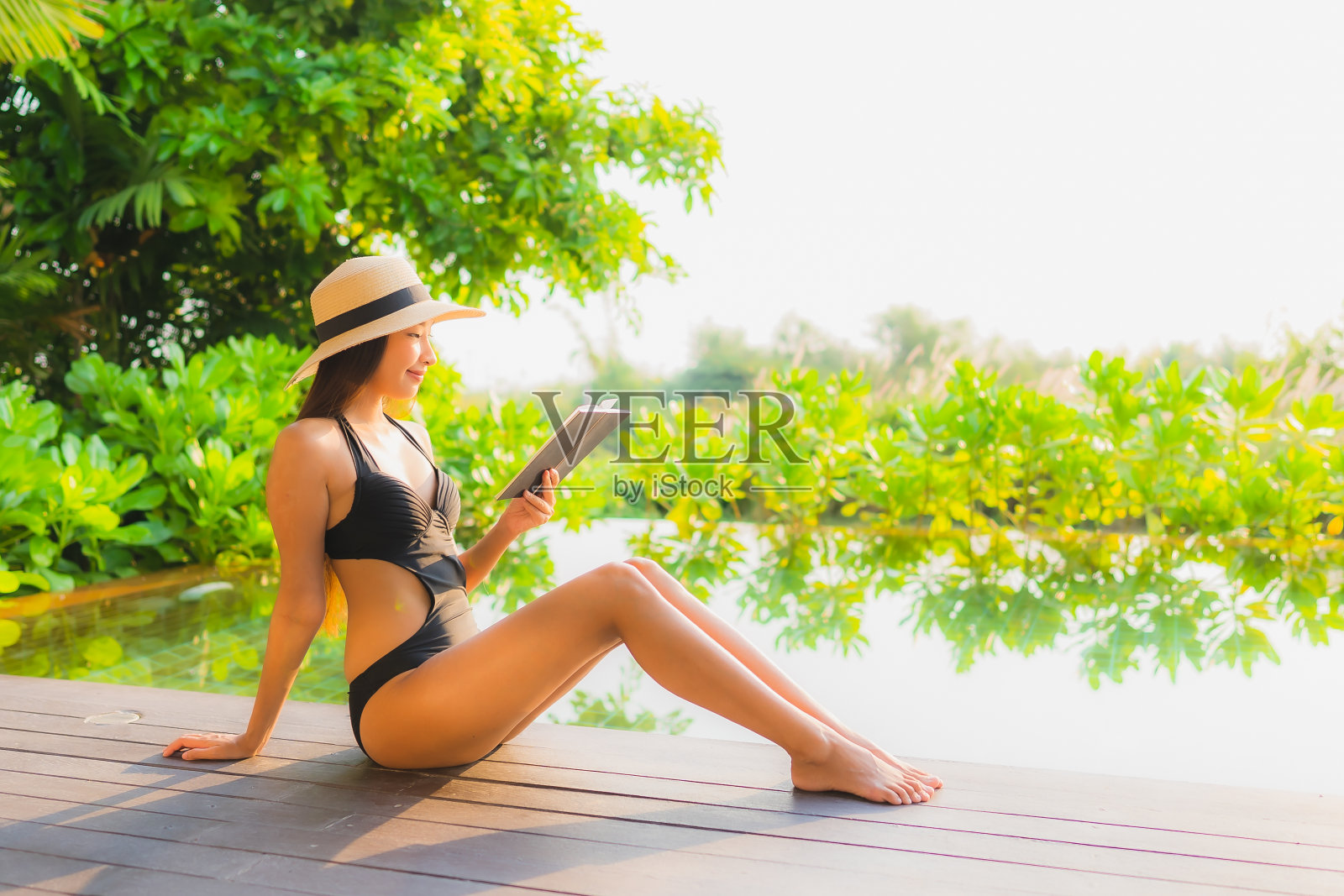 在酒店游泳池放松的年轻亚洲女性照片摄影图片