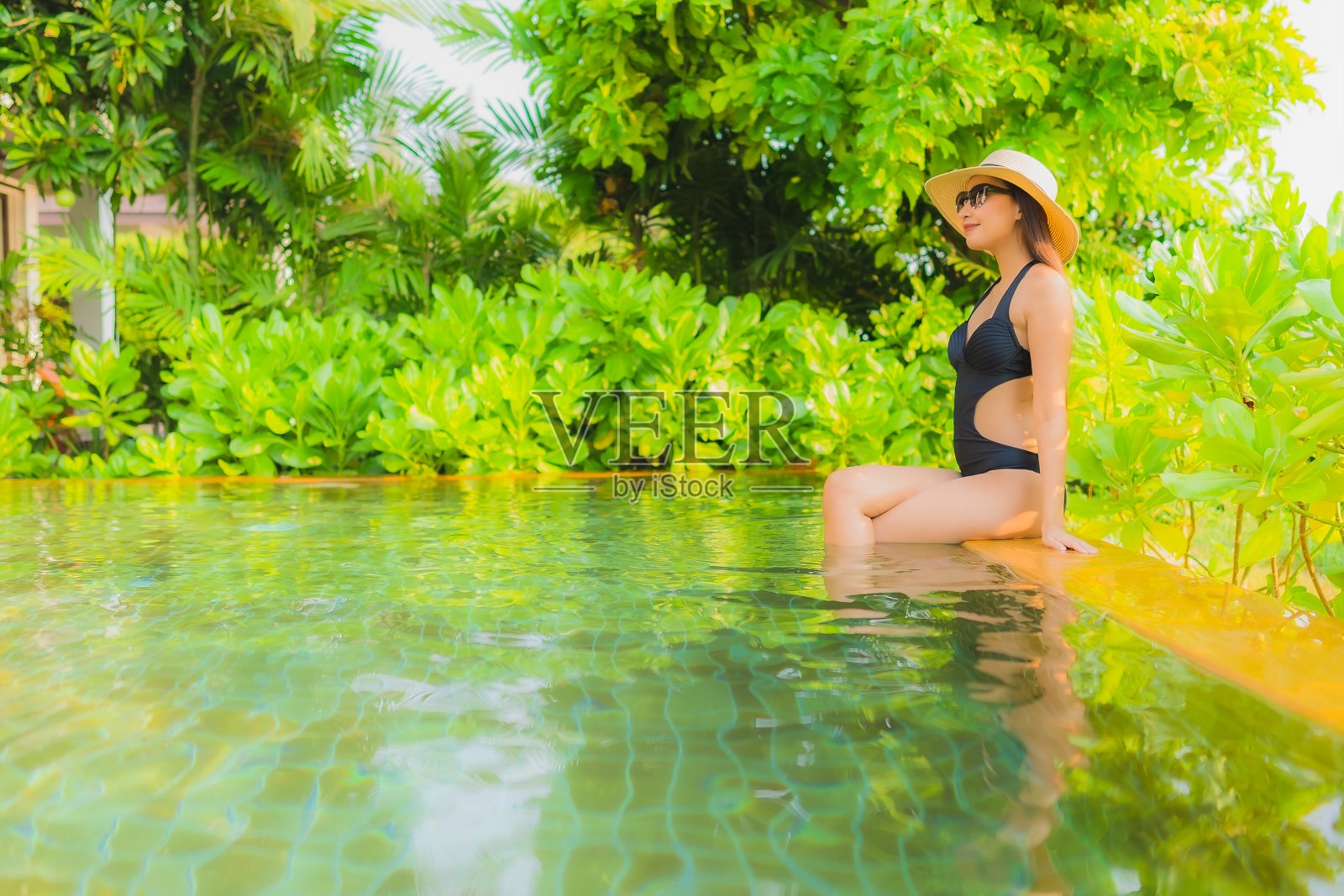 在酒店游泳池放松的年轻亚洲女性照片摄影图片