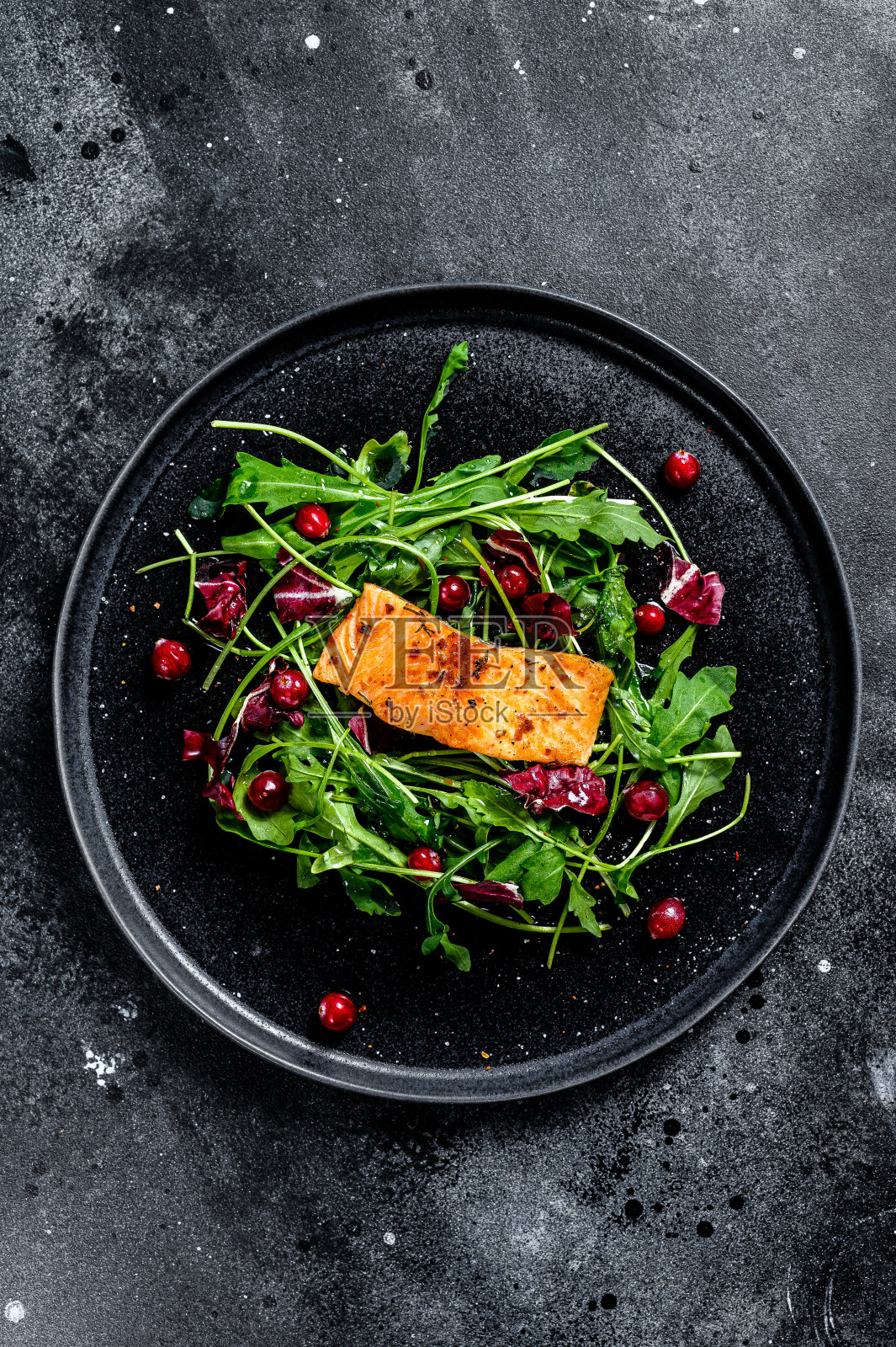 海鲜沙拉鲑鱼,芝麻菜,莴苣和蔓越莓。黑色背景。俯视图照片摄影图片