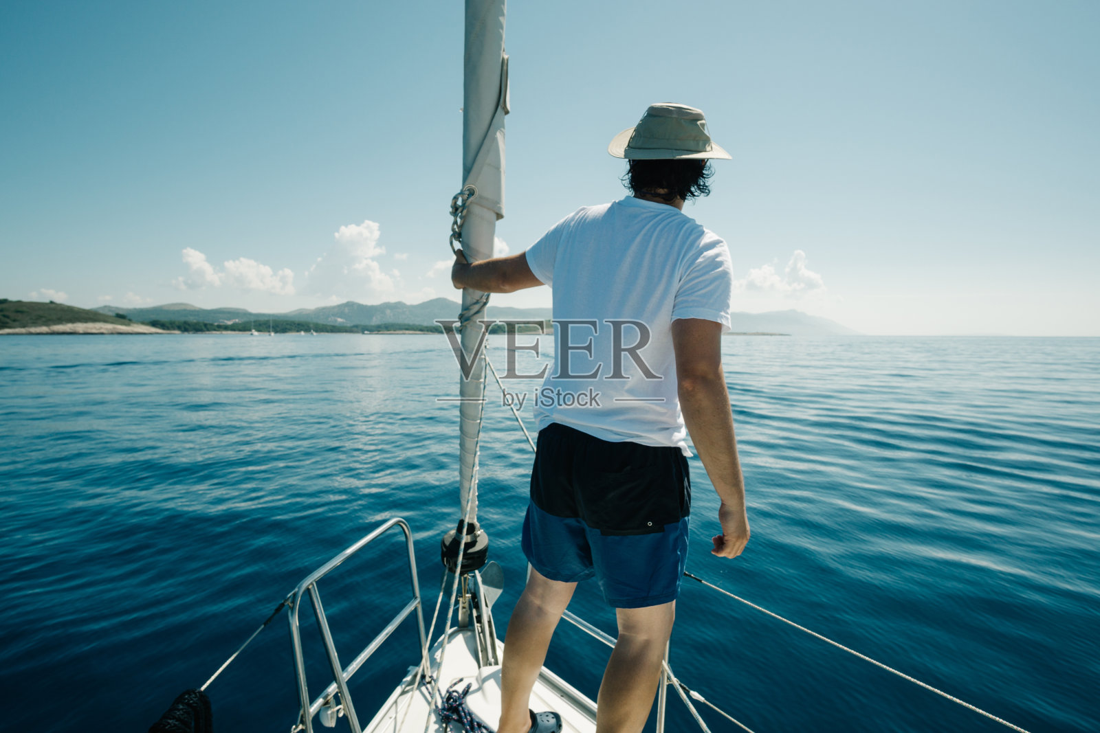 人站在船头享受游艇之旅。帆船,游艇和旅游的概念。照片摄影图片