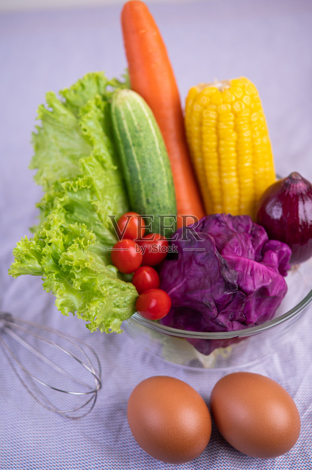 西红柿,胡萝卜,黄瓜,洋葱,沙拉,鸡蛋,洋葱和紫甘蓝放在一个玻璃杯里。有选择性的重点照片摄影图片