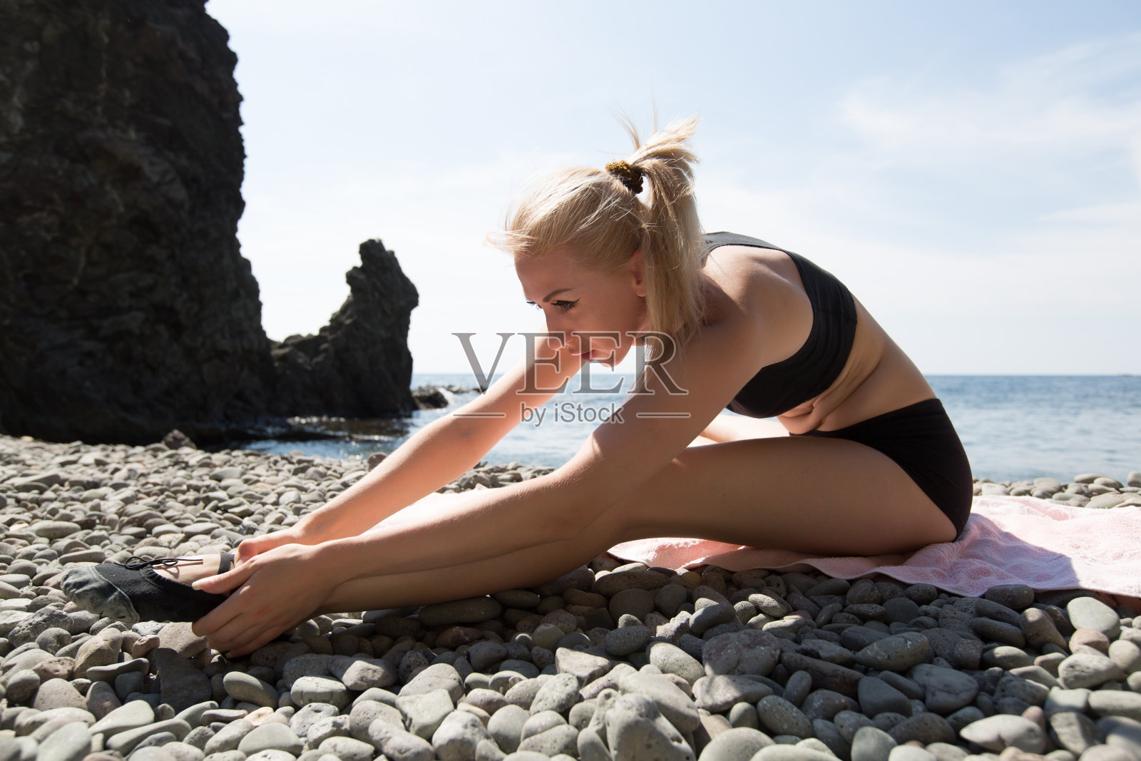 身材苗条的年轻女子在砾石滩上训练照片摄影图片