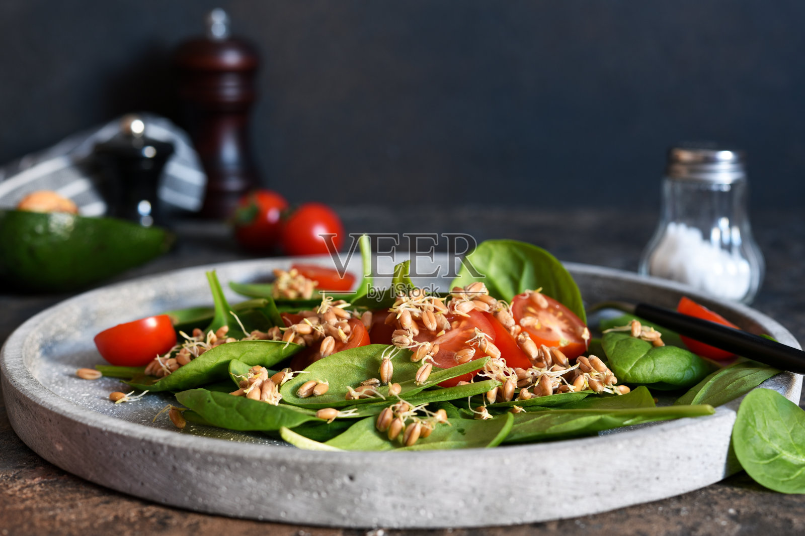 把菠菜、西红柿和小麦幼苗放在混凝土盘子里做成沙拉。照片摄影图片