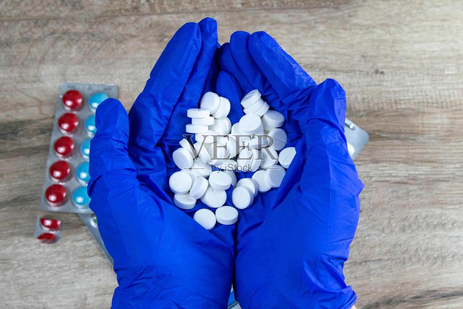 许多白色小药丸在医生的手中戴着医用蓝色一次性手套照片摄影图片