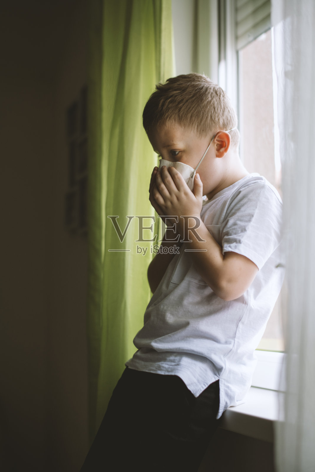 小男孩戴着防护面具,呆在家里照片摄影图片