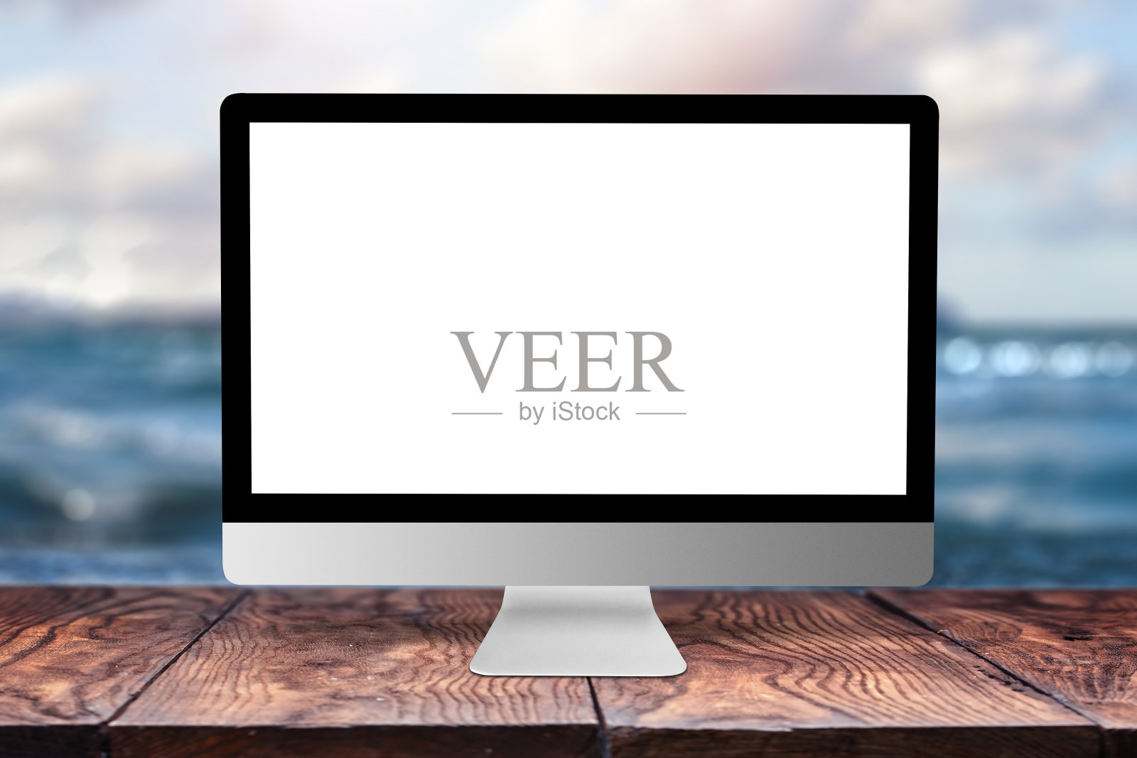 模拟电脑显示在木桌上,以大海为背景。照片摄影图片