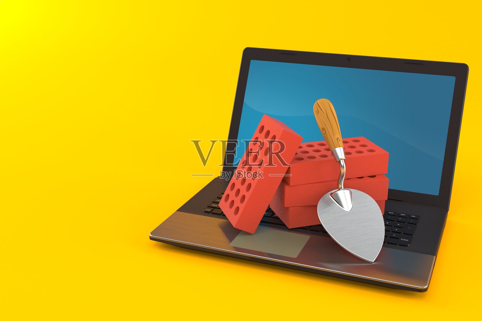 带笔记本电脑的泥铲和砖块照片摄影图片