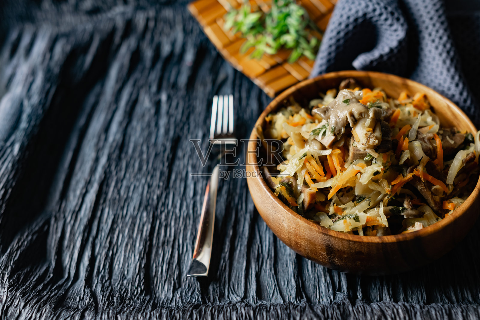 洋白菜配平菇,猪舌配胡萝卜和洋葱。木架子上的木盘子里的热菜照片摄影图片