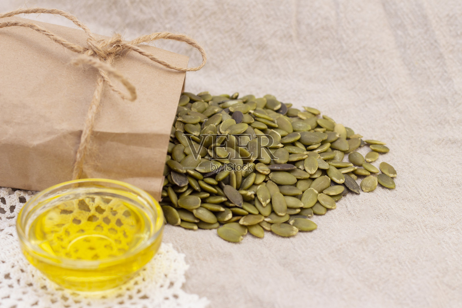 南瓜籽装在纸袋里,南瓜籽油放在天然亚麻上。南瓜籽B族维生素和镁。照片摄影图片