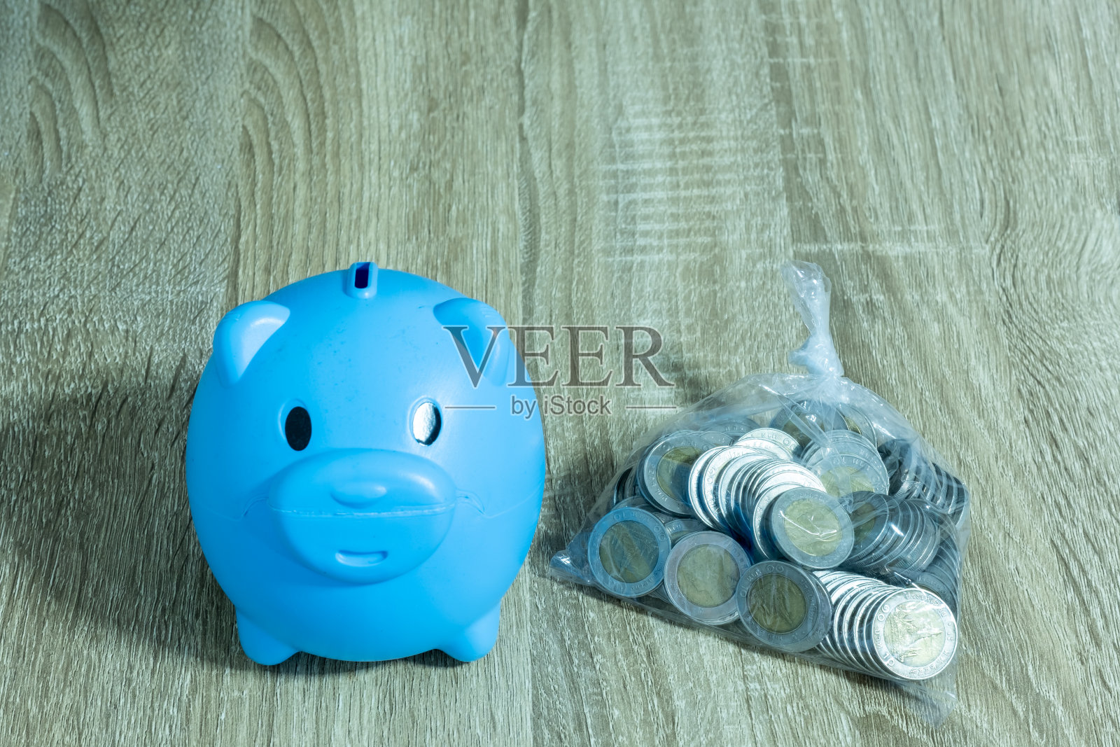 特写蓝色储蓄罐和硬币放在木桌上,概念省钱照片摄影图片