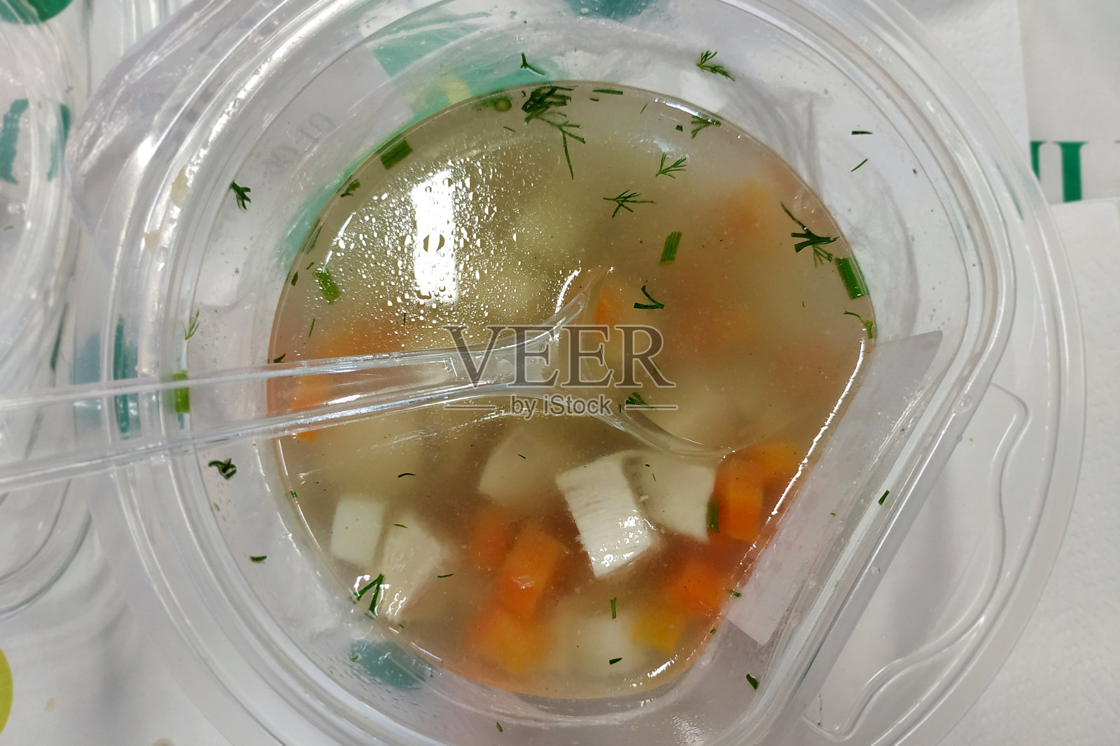 用勺子把鸡汤盛在塑料碗里照片摄影图片