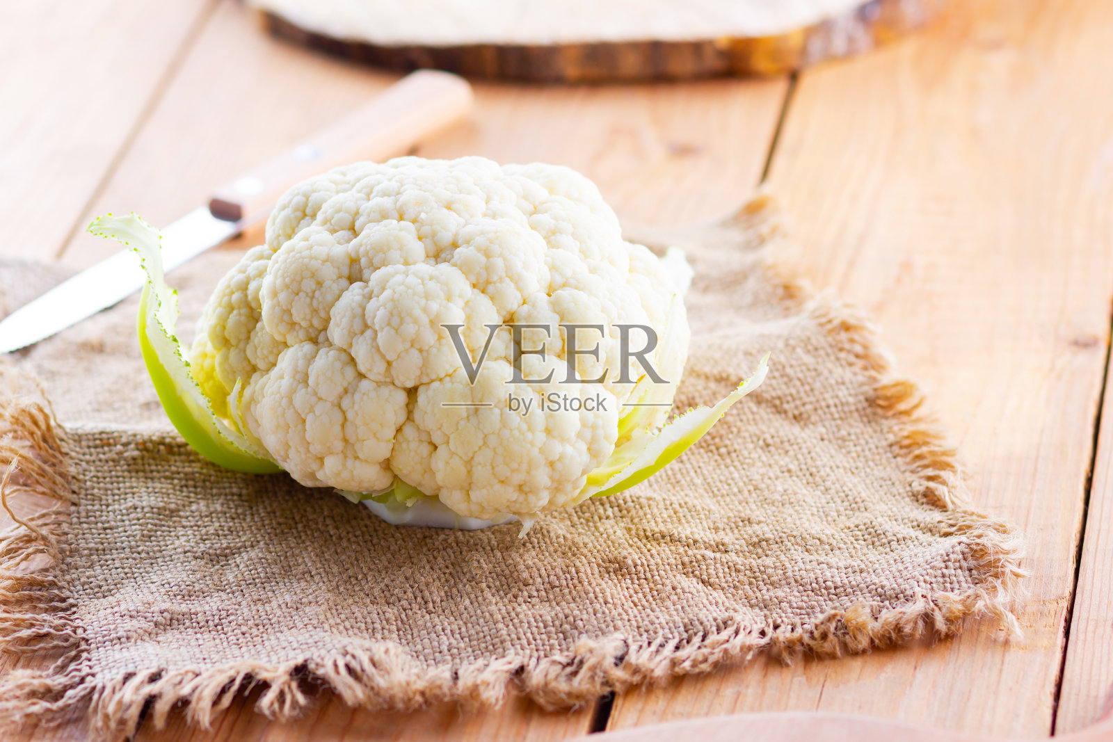 木制背景上的有机菜花。麻袋上的花椰菜头。有机食品。乡村风格照片摄影图片