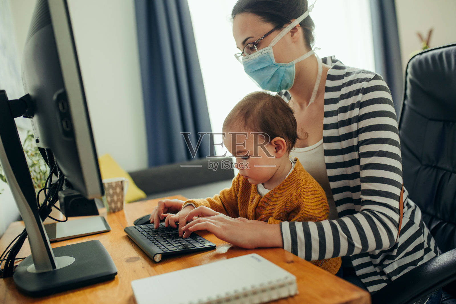 年轻母亲在家里办公室用电脑和她的宝宝一起工作照片摄影图片