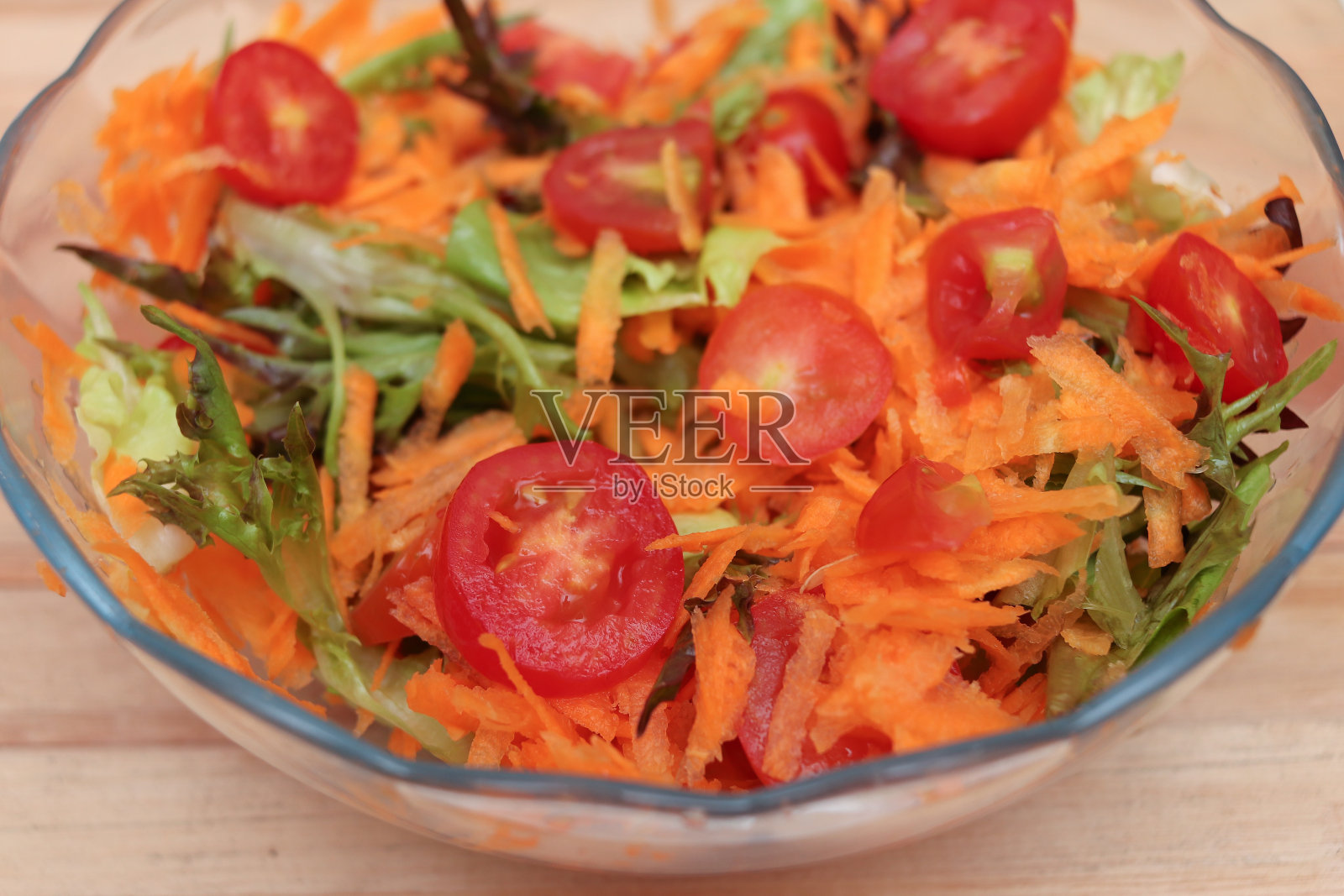 沙拉碗,里面有西红柿、胡萝卜和叶子照片摄影图片