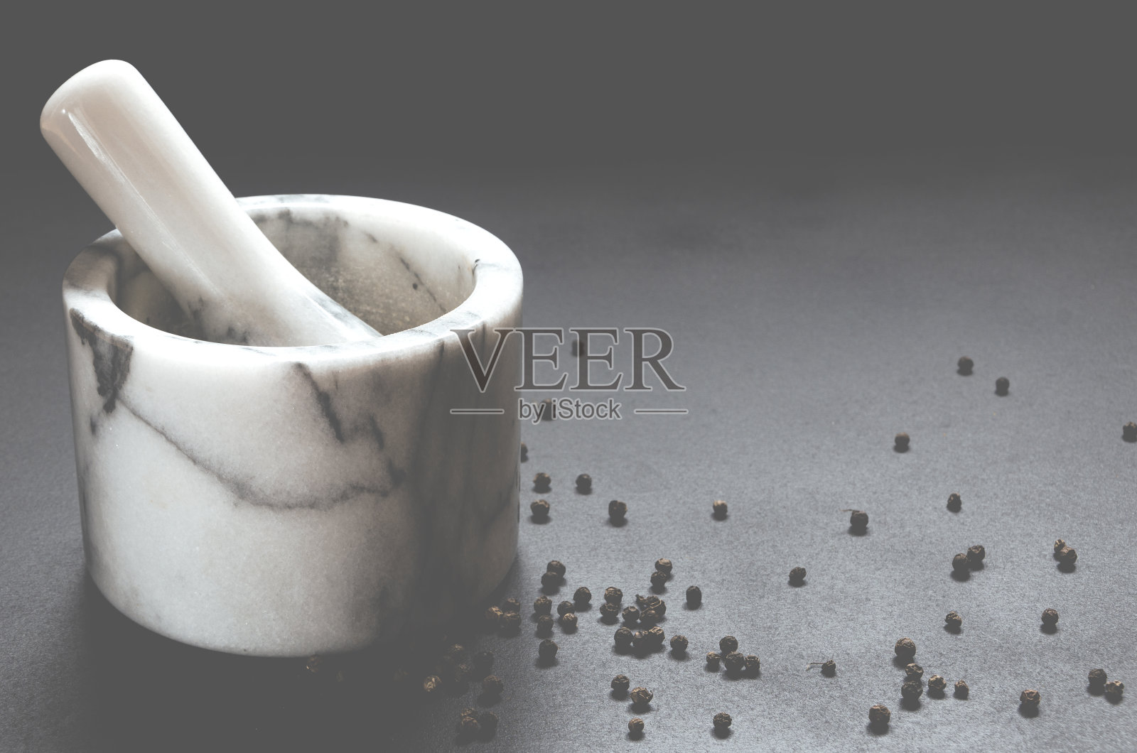 用来磨胡椒的大理石砂浆放在黑色的背景上。照片摄影图片