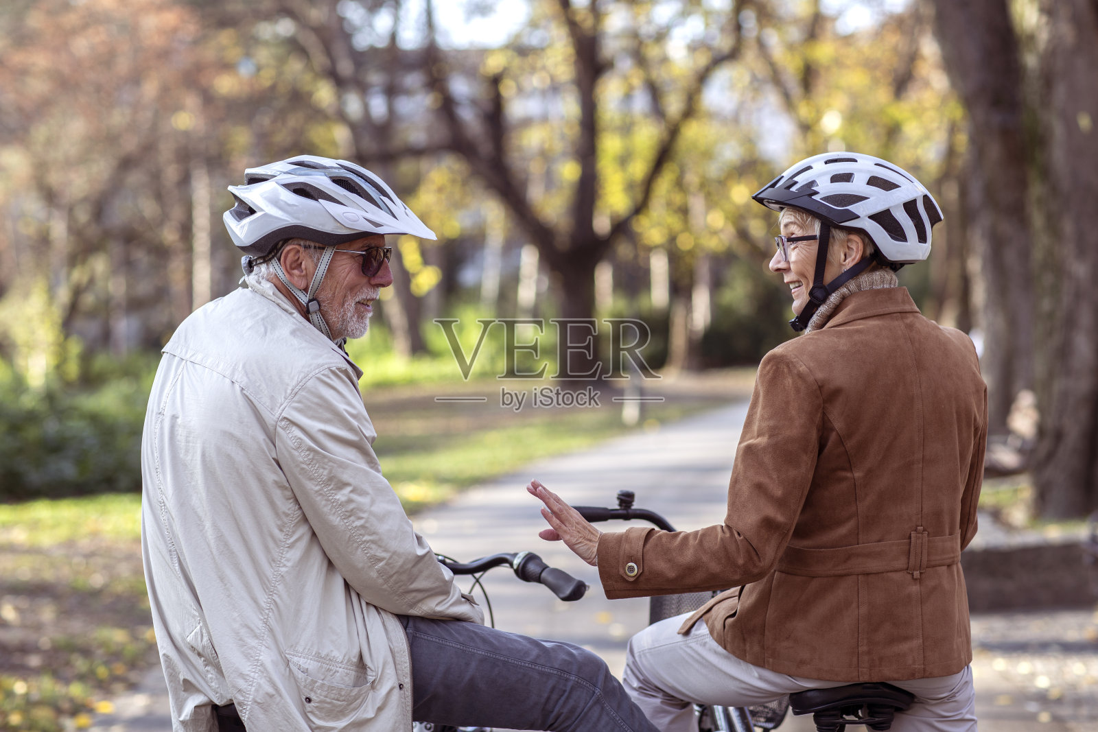 公园里骑着自行车戴着头盔的老夫妇照片摄影图片