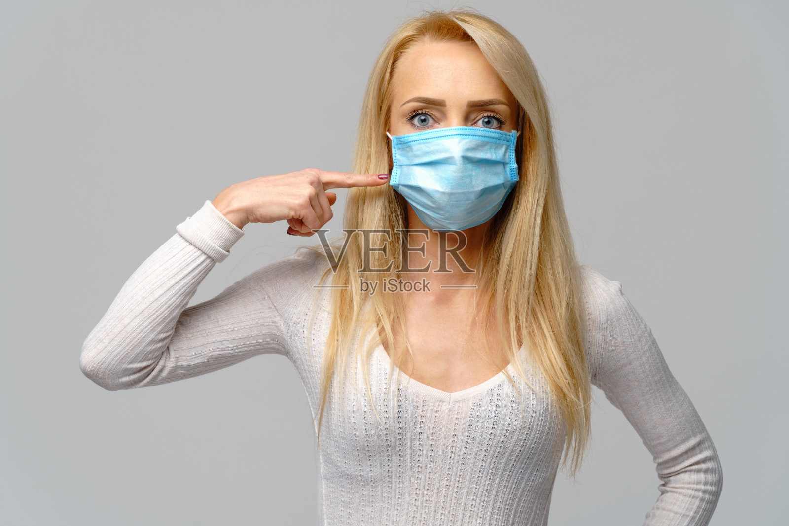 戴防护口罩的年轻女子在灰色背景下的工作室肖像-流感病毒流行病防护,灰尘或花粉过敏,空气污染照片摄影图片