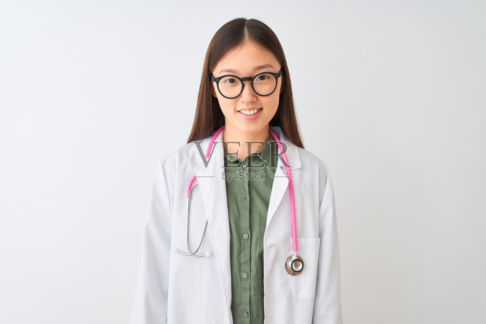 年轻的中国女医生戴眼镜听诊器在孤立的白色背景与快乐和凉爽的微笑在脸上。幸运的人。照片摄影图片
