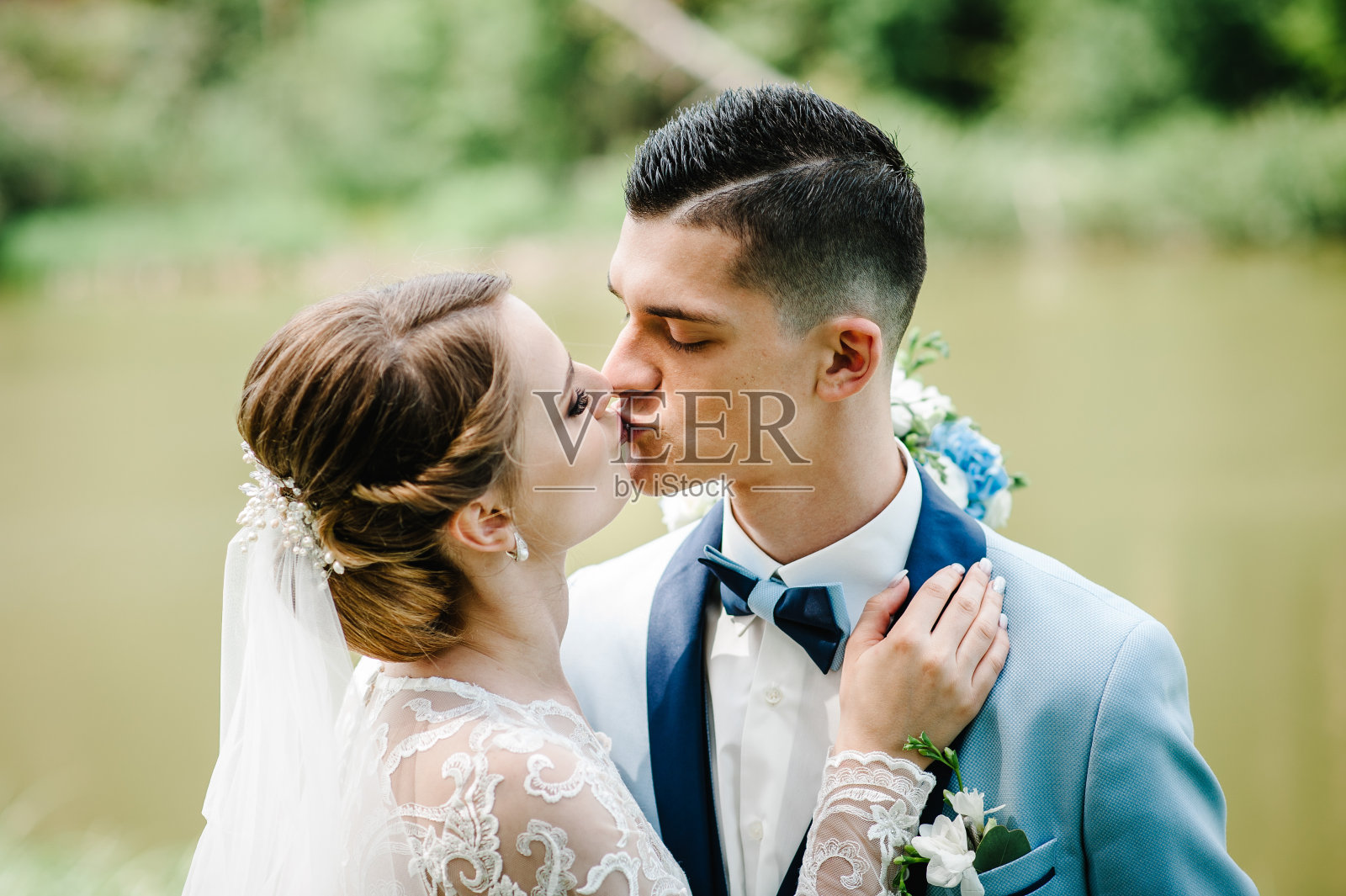 新娘和新郎在婚礼后亲吻大自然。一对新婚夫妇在绿色的背景下。照片摄影图片