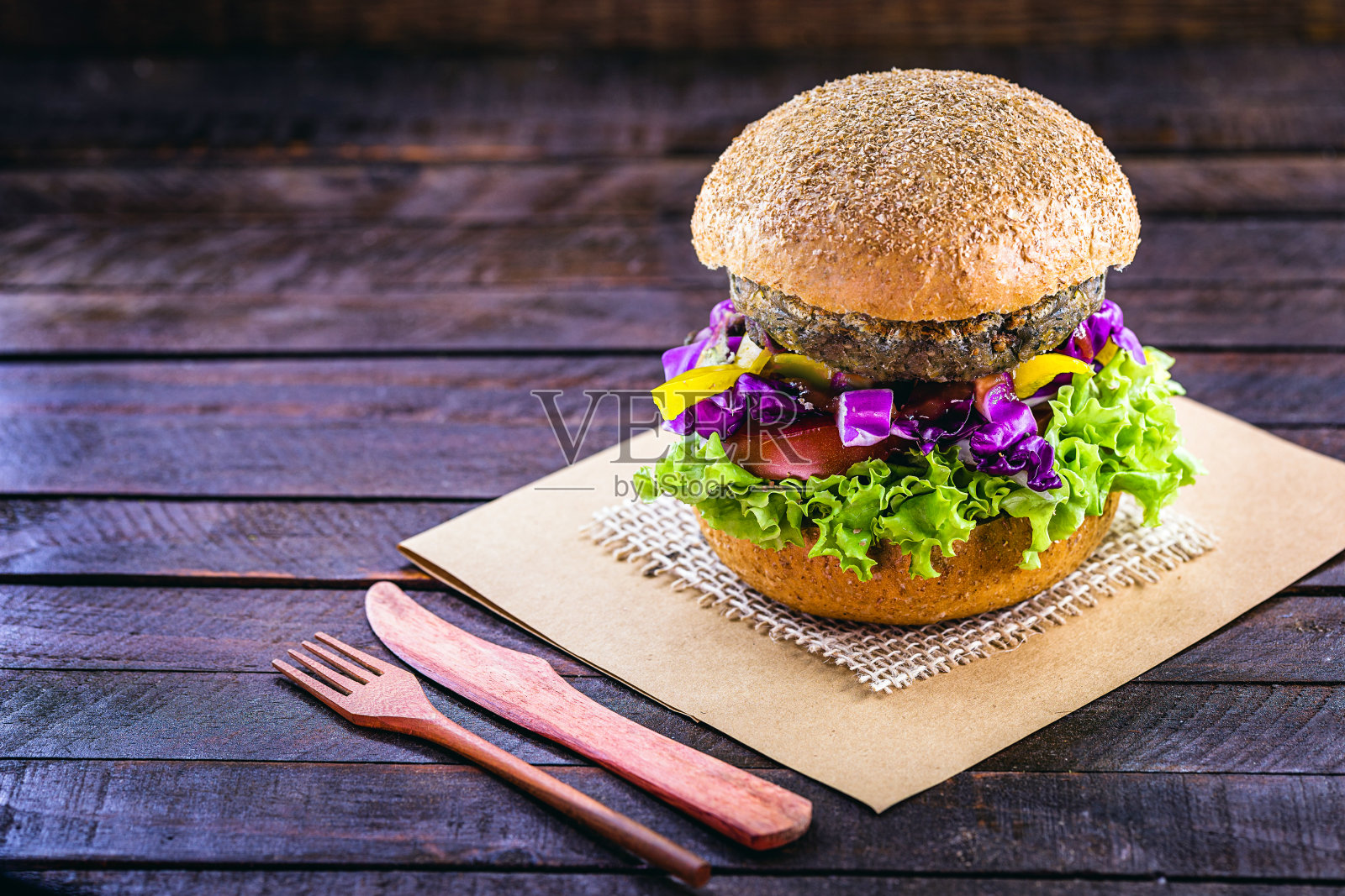 素食汉堡,烤熟后即可食用。健康素食的生活理念。以大豆和鹰嘴豆为基础的无肉零食,在黑色的乡村木材背景上配以新鲜蔬菜照片摄影图片