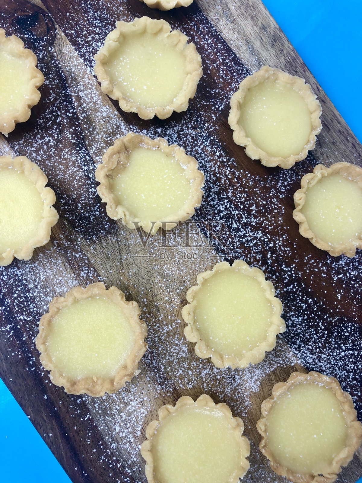 形象的排小自制,酥皮柠檬凝乳馅饼撒糖粉在木板上,绿松石背景照片摄影图片