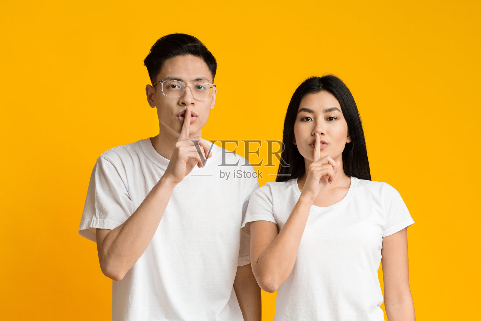 严肃的亚洲夫妇做沉默手势,食指放在嘴唇上照片摄影图片