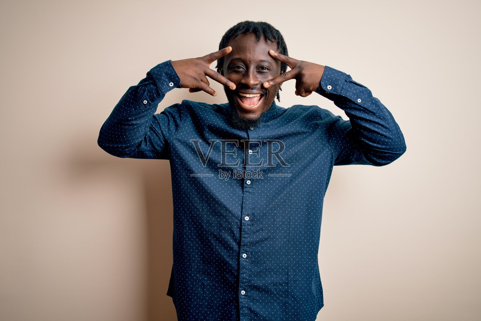 年轻英俊的非裔美国人穿着休闲衬衫站在白色的背景做和平的象征,手指在脸上,微笑的快乐显示胜利照片摄影图片