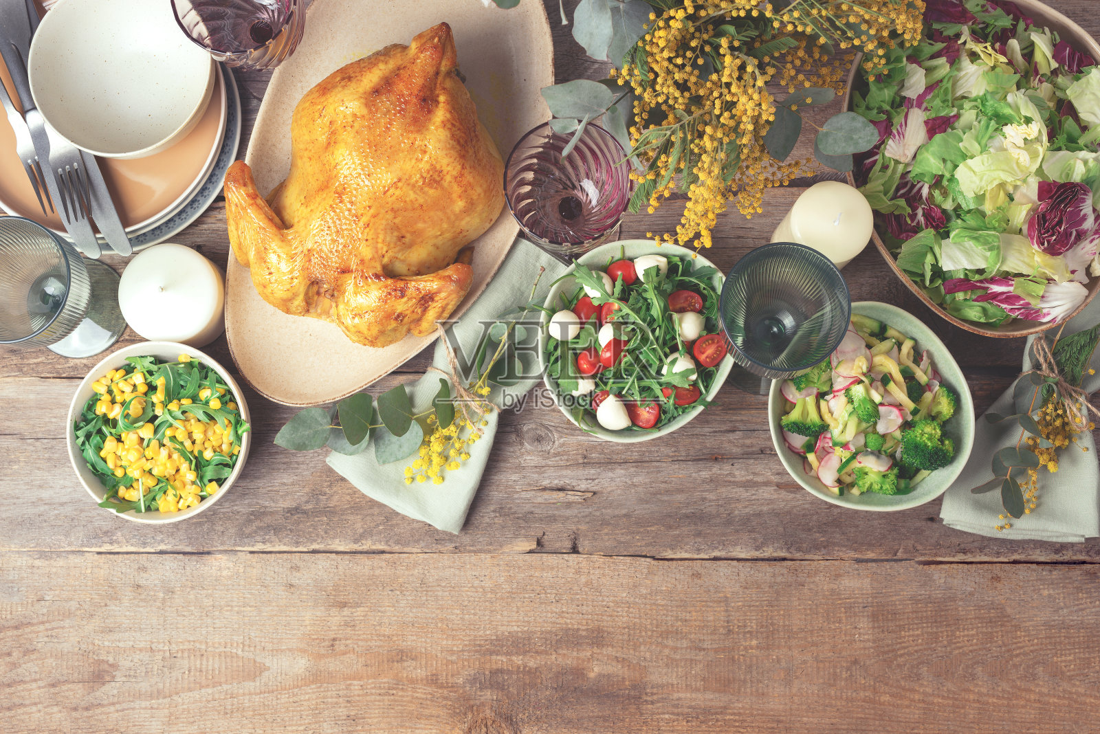 情人节,妇女节,母亲节,婚礼早午餐,节日家庭午餐和晚餐的概念。节日家庭餐桌。盛有沙拉和蔬菜的盘子,碗,小吃,烤鸡,桉树,含苞欲放的花照片摄影图片