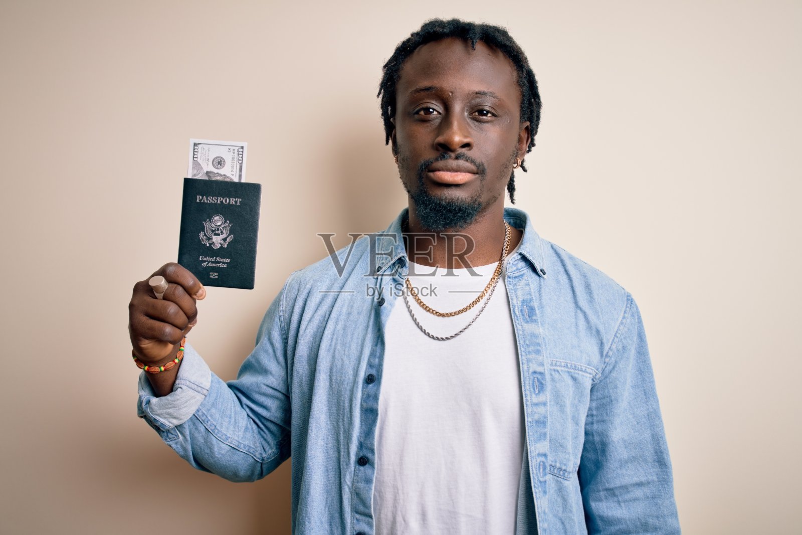 年轻的非洲裔美国游客男子拿着护照与美元钞票作为钱旅行与自信的表情在聪明的脸上思考认真照片摄影图片
