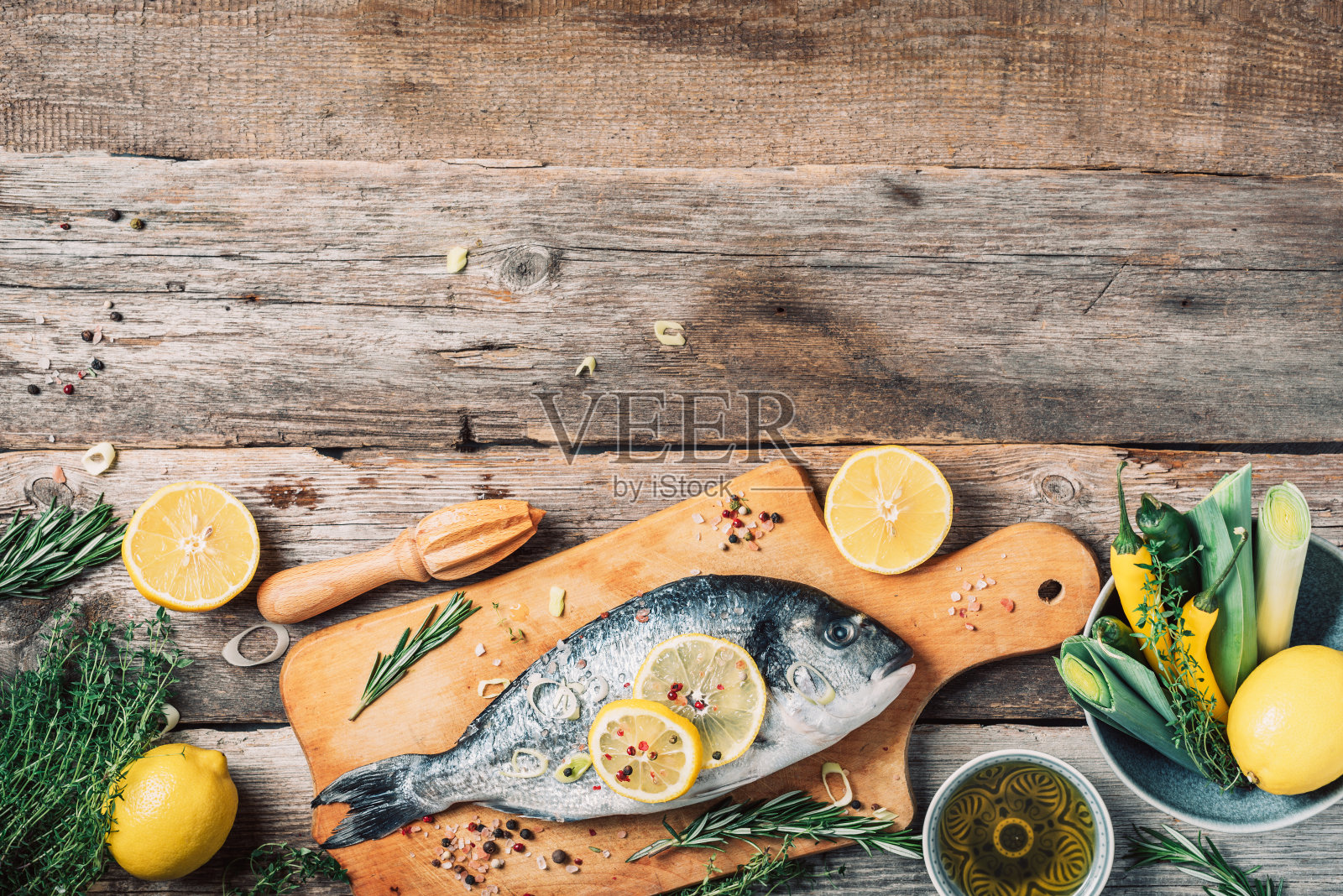 新鲜多拉多鱼食材配料:柠檬、香草、油、蔬菜和香料,木制砧板背景。健康饮食海鲜理念。照片摄影图片