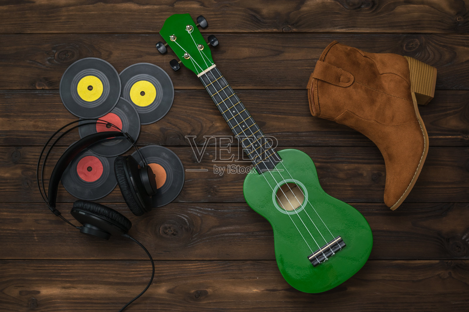 绿色的尤克里里琴,耳机,绒面革靴子和乙烯基唱片在一个木制的背景。照片摄影图片