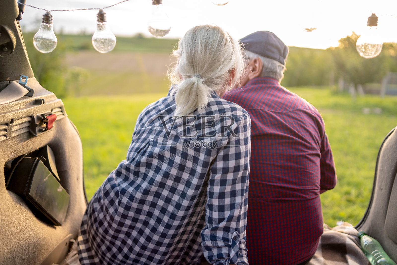 一对快乐的老夫妇坐在他们的汽车后备箱里照片摄影图片