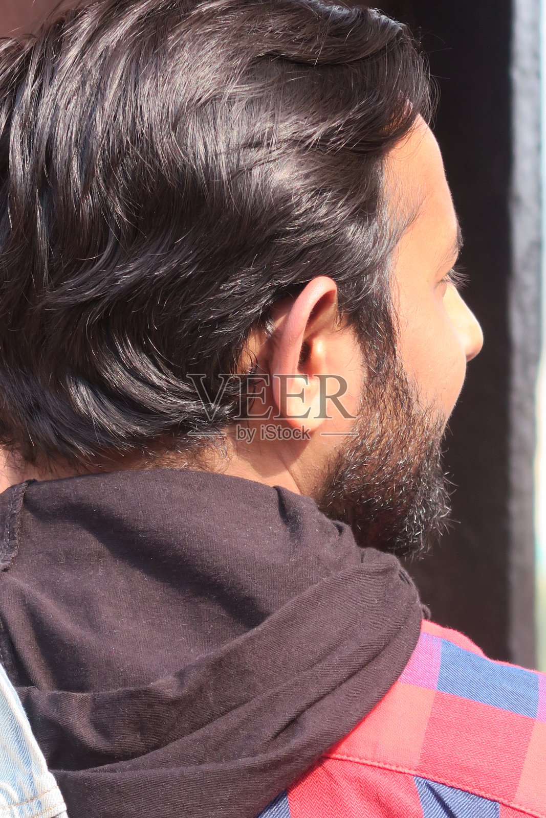 年轻黝黑的印度男子,身穿红色格子连帽衫,在印度德里照片摄影图片