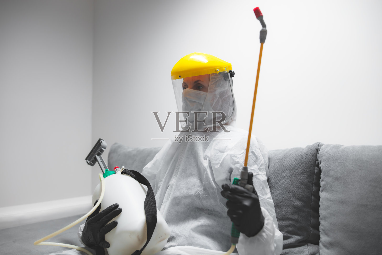 佩戴防护口罩,在家隔离并使用化学消毒喷雾的人照片摄影图片