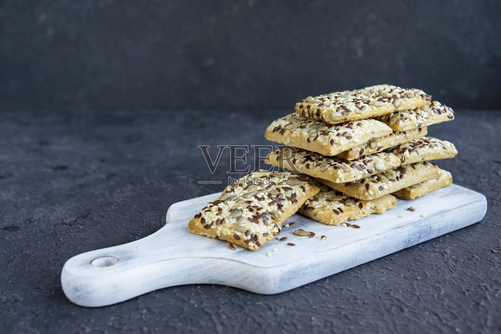 脆脆的面包和种子在乡村的白板,黑色的背景。健康的零食:照片摄影图片