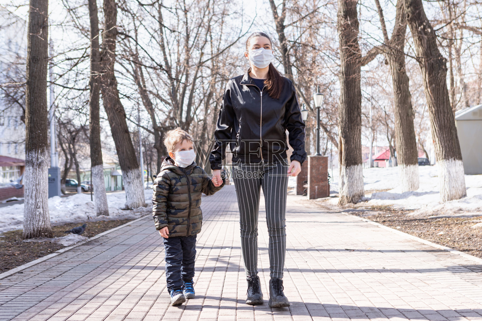 母亲和孩子戴着口罩走在街上,预防新冠疫情照片摄影图片